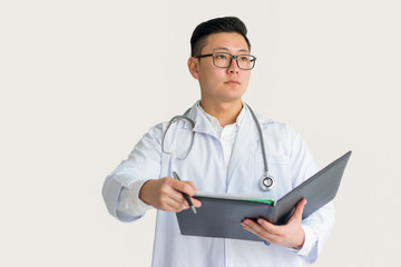 Serious Young Asian Doctor Holding Clipboard