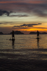 two man silhouette standing on sup boards on sunset time in El Nido, Palawan, Philippines, Corong Corong beach