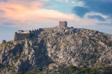 Fototapeta na wymiar Old fortress Starigrad on the top of the rocky peak of Dinara mountains, sunset view, Omis, Croatia