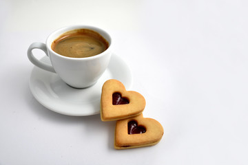 Cookie with coffee stock images. Cup of coffee on a white background. White cup of coffee with snack. Cup of coffee with cookie. Espresso with sweetness. Sweet biscuits hearts