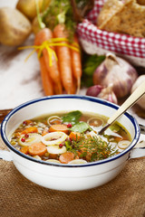 Vegetable soup in a metal bowl on a rural rustic wooden table.