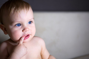 Cute kid with blue eyes. Cute little child with blue eyes putting finger to mouth.