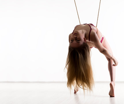 Perfect slim girl with a rope posing on a light background. Sexy athletic body. free space for your text