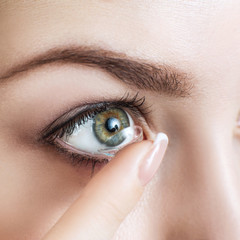 Close-up shot of young woman wearing contact lens.