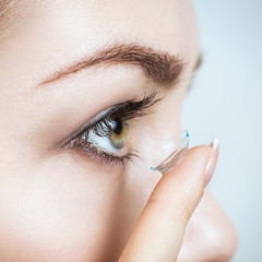 Close-up shot of young woman wearing contact lens.