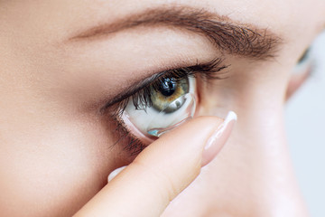 Close-up shot of young woman wearing contact lens. - 192145282
