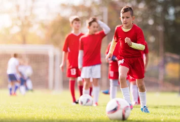 Foto op Plexiglas Boy kicking football on the sports field © Dusan Kostic