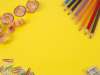 Some colored pencils of different colors and a pencil sharpener and pencil shavings on а yellow background