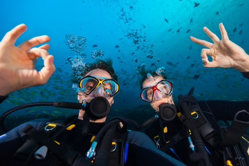 Couple of scuba divers showing ok sign, portrait photography