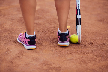 Fototapeta na wymiar Close-up women's legs of sportive girl near the tennis racquet and ball.
