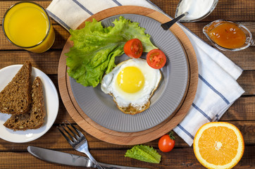 English Breakfast: fried egg, juice, cherry tomatoes, lettuce, grain bread, sauce, top view.