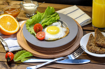 English Breakfast: fried egg, juice, cherry tomatoes, lettuce, grain bread, sauce, top view.