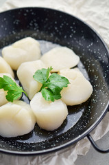 Raw scallops with herbs on frying pan