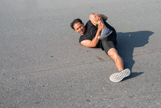 Male runners are stretching the leg muscles to prepare for a run in the morning. The concept of health and fitness