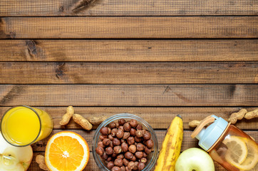 Healthy lifestyle; fitness bottle; fruits (oranges; apples and bananas); hazelnuts and peanuts; orange juice and measuring tape. Top view; the concept of free space for text