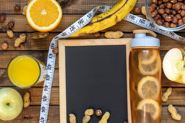 Healthy lifestyle; fitness bottle; fruits (oranges; apples and bananas); hazelnuts and peanuts; orange juice and measuring tape. Top view; the concept of free space for text