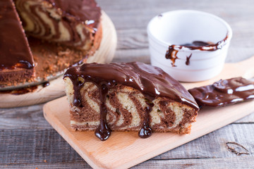 Piece of ''Zebra'' cake with chocolate glaze on wooden table
