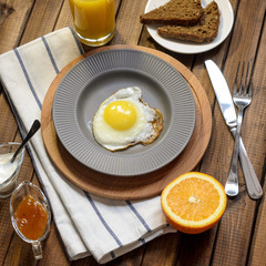 English Breakfast: fried egg, juice, cherry tomatoes, lettuce, grain bread, sauce, top view.