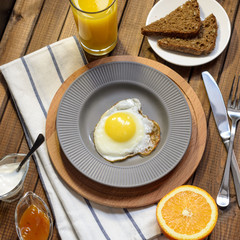 English Breakfast: fried egg, juice, cherry tomatoes, lettuce, grain bread, sauce, top view.