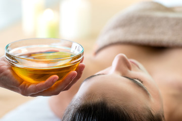 Hand holding bowl with aromatic oil in spa.
