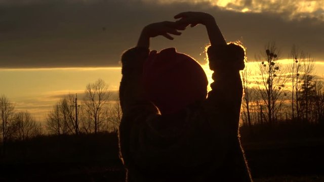Small girl raises his hands up against the sun leaving for horizon (sunset), feeling freedom 