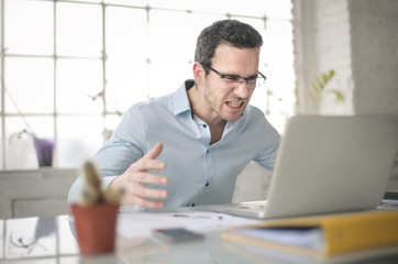 Furious businessman screaming in front of his laptop