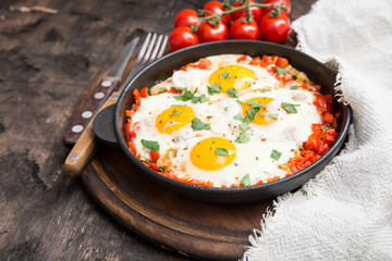 Tasty and Healthy Shakshuka in a Frying Pan. Fried eggs with tomatoes, bell pepper, vegetables and herbs. Middle eastern traditional dish.