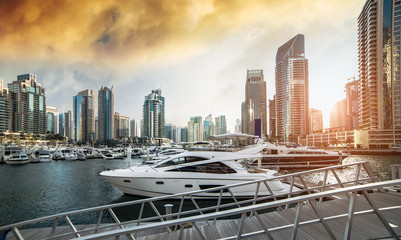 Fototapeta na wymiar view with modern skyscrapers and water pier of Dubai Marina at sunset, United Arab Emirates