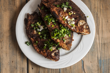 Fried fish crucian in plate on wooden table
