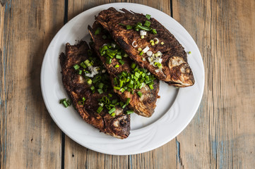 Fried fish crucian in plate on wooden table