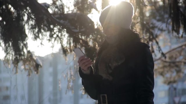 Girl uses a smartphone in winter