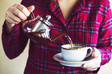 A girl in red checkered pajamas pours morning tea