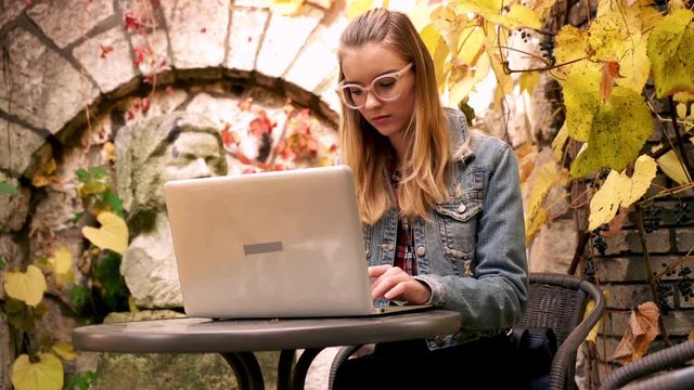 Young, pretty woman working on laptop in the garden
