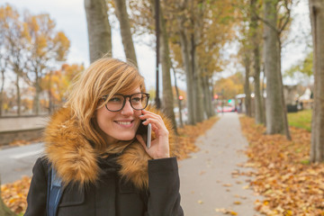 Cute woman walking on a sidewalk in autumn surroundings.