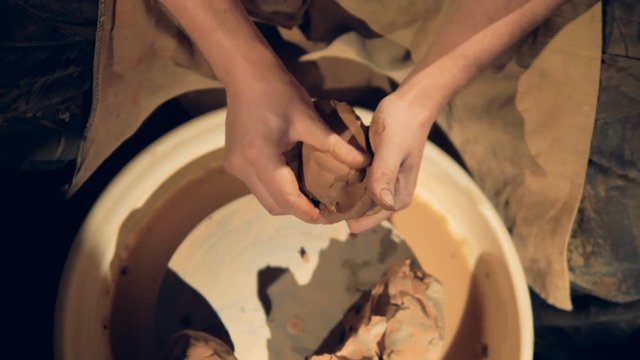 A close view on potters hands kneading clay. 