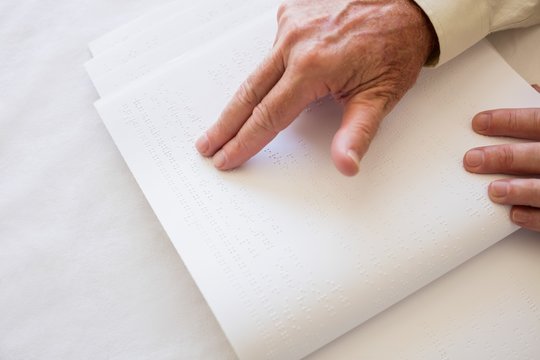 Blind senior woman using braille to read