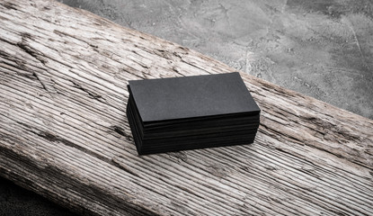 Stack of black blank name cards on wooden background. Mockup for branding company style.