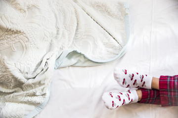 Female legs in pajamas and socks on the bed. Background. Home morning concept