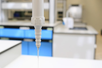 Closeup plastic tap turn on with water running to sink in chemical laboratory class blurred...