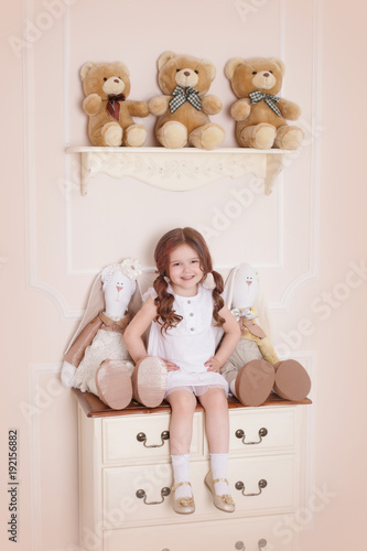 A Little Girl In Her Room Sitting On A Chest Of Drawers With Toys