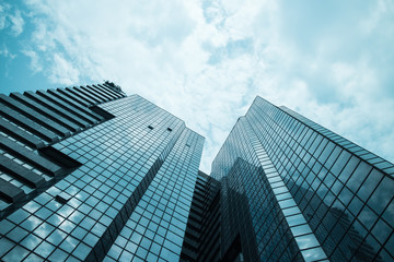 glass reflective office buildings against blue sky with clouds and sun light.