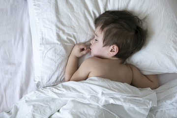 Obraz na płótnie Canvas Peaceful baby lying on a bed while sleeping in a bright room. cute two year old Asian boy on white the pillow