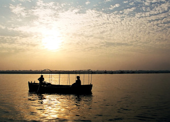 Silhouettes of people on the boat at the river Ganges in Varanasi, India at sunrise