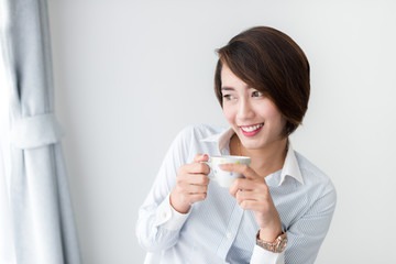 Businesswoman drinking coffee and looking out window.