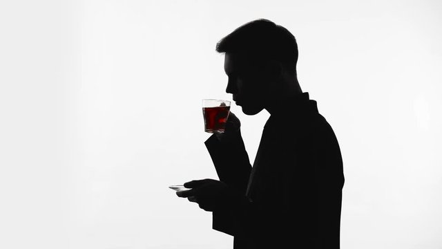 Dark silhouette of man drinking glass of tea, recreation, pH balance restore
