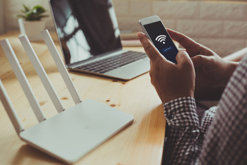 closeup of a wifi router and a man using smartphone on living room at home ofiice