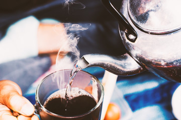 Woman pours boiling water into the cup of coffee