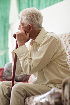 Thoughtful senior man sitting with a cane