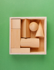 wooden geometric shapes in a box on a green background