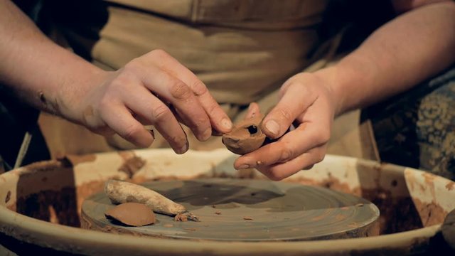A potter manually shapes a clay spoon. 